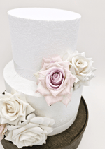Artificial wedding cake decoration close-up with ivory and pale lavender faux roses arranged between two tiers. For birthday, event and celebration cakes. Made in Melbourne by Flowers For Ever After, shipping Australia and Worldwide.
