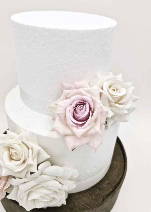 Artificial wedding cake decoration close-up with ivory and pale lavender faux roses arranged between two tiers. For birthday, event and celebration cakes. Made in Melbourne by Flowers For Ever After, shipping Australia and Worldwide.