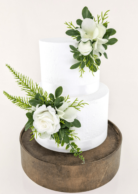 Artificial wedding cake decoration, angled view of white faux roses, orchids, green leaves and fern-like foliage. For birthday, event and celebration cakes. Made in Melbourne by Flowers For Ever After, shipping Australia and Worldwide.
