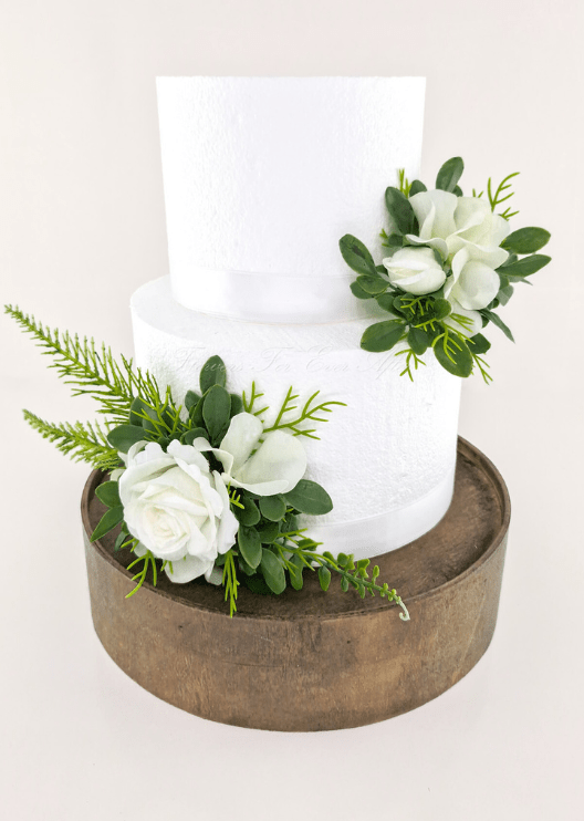 Artificial wedding cake decoration with white faux roses, white orchids, green leaves and fern-like foliage in two clusters. For birthday, event and celebration cakes. Made in Melbourne by Flowers For Ever After, shipping Australia and Worldwide.