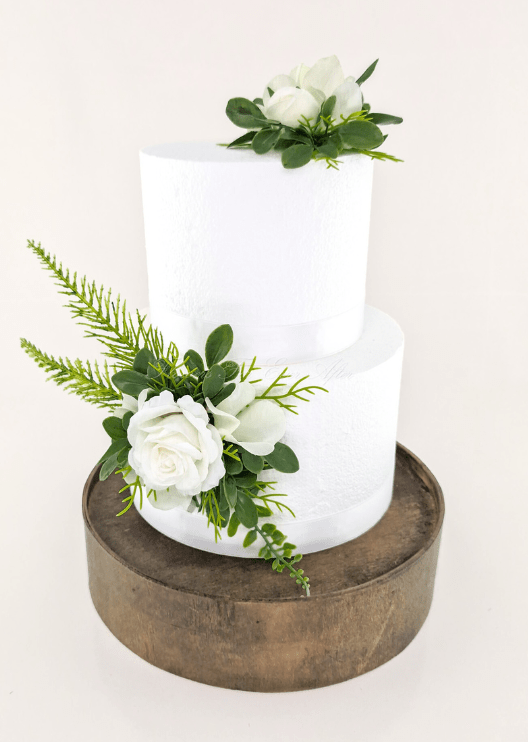 Artificial wedding cake decoration with white faux roses, white orchids and green foliage placed on top and at the lower tier. For birthday, event and celebration cakes. Made in Melbourne by Flowers For Ever After, shipping Australia and Worldwide.