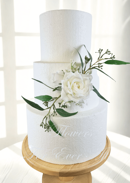 Artificial wedding cake decoration with white and dusty pink faux roses, berry sprigs and fine green foliage arranged over two tiers. For birthday, event and celebration cakes. Made in Melbourne by Flowers For Ever After, shipping Australia and Worldwide.