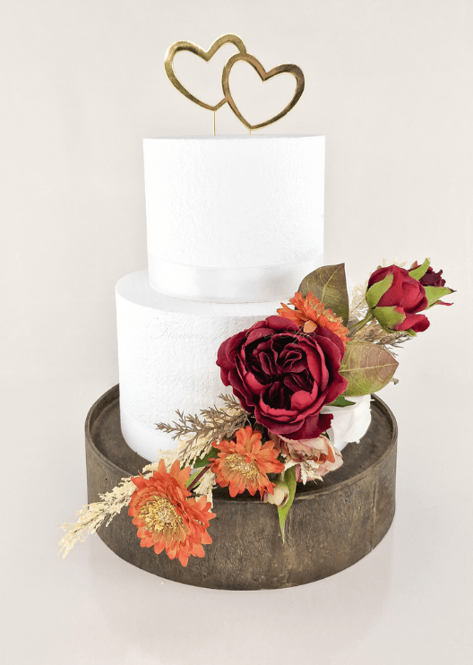 Artificial wedding cake decoration with burgundy faux blooms, orange daisies, pale filler flowers and bronze-green leaves. For birthday, event and celebration cakes. Made in Melbourne by Flowers For Ever After, shipping Australia and Worldwide.
