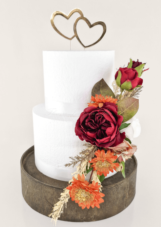 Artificial wedding cake decoration, front view of burgundy faux blooms, orange daisies and bronze-green leaves. For birthday, event and celebration cakes. Made in Melbourne by Flowers For Ever After, shipping Australia and Worldwide.