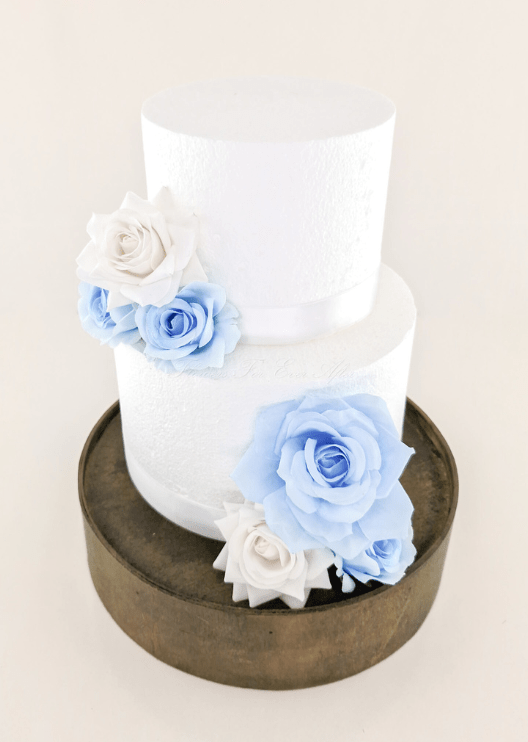 Artificial wedding cake decoration, angled view of light blue and white faux rose clusters across the tiers. For birthday, event and celebration cakes. Made in Melbourne by Flowers For Ever After, shipping Australia and Worldwide.