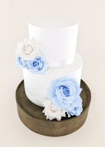 Artificial wedding cake decoration, angled view of light blue and white faux rose clusters across the tiers. For birthday, event and celebration cakes. Made in Melbourne by Flowers For Ever After, shipping Australia and Worldwide.