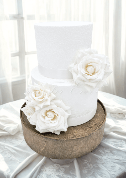 Artificial wedding cake decoration with ivory faux roses and green leaves arranged across two tiers. For birthday, event and celebration cakes. Made in Melbourne by Flowers For Ever After, shipping Australia and Worldwide.