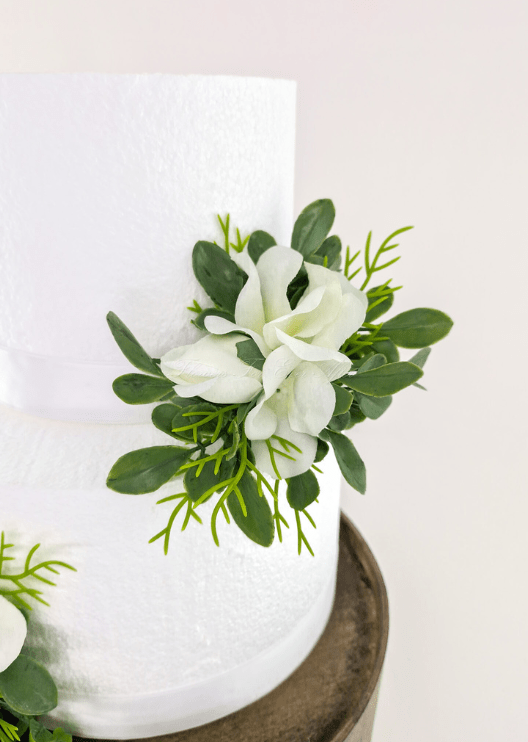 Artificial wedding cake flower detail showing white faux orchids, rosebuds and rounded green leaves. For birthday, event and celebration cakes. Made in Melbourne by Flowers For Ever After, shipping Australia and Worldwide.