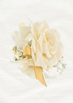 Artificial wedding wrist corsage, side view of layered ivory faux rose petals, pale sprigs and gold-edged yellow ribbons. For formals, proms and ball occasions. Made in Melbourne by Flowers For Ever After, shipping Australia and Worldwide.