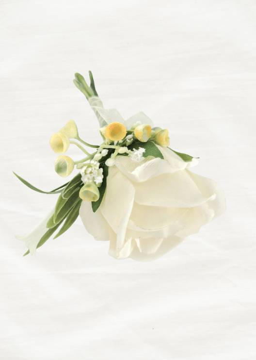 Artificial wedding boutonniere, top view of an ivory faux rose, yellow-tipped sprigs, tiny white flowers and green leaves. For formals, proms and ball occasions. Made in Melbourne by Flowers For Ever After, shipping Australia and Worldwide.