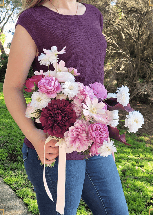 Artificial wedding bridal bouquet held by a bride, with lilac, burgundy and white faux flowers and green foliage. Made in Melbourne by Flowers For Ever After, shipping Australia and Worldwide.