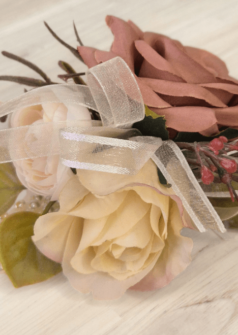 Artificial wedding corsage close-up with champagne and dusty pink faux roses, ivory ribbon loops and pink berry sprigs. For formals, proms and ball occasions. Made in Melbourne by Flowers For Ever After, shipping Australia and Worldwide.