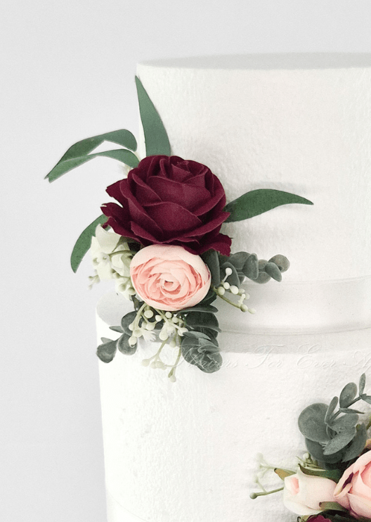 Artificial wedding cake flower close-up with burgundy and blush faux roses, tiny white flowers and eucalyptus at the tier join. For birthday, event and celebration cakes. Made in Melbourne by Flowers For Ever After, shipping Australia and Worldwide.