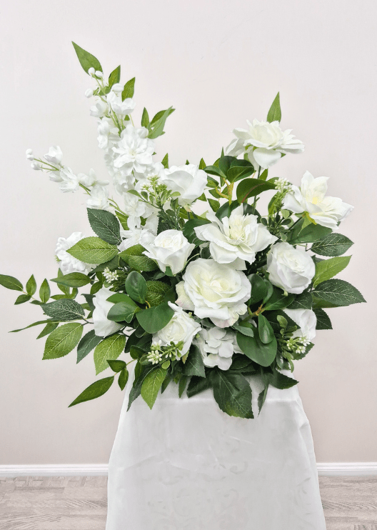 Artificial wedding pedestal arrangement with white faux roses, open blooms, tall white flower spikes and broad green leaves. Made in Melbourne by Flowers For Ever After, shipping Australia and Worldwide.