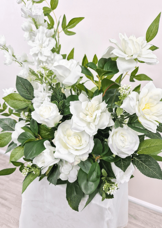 Artificial wedding ceremony flower close-up with white faux roses, open layered blooms, tiny buds and broad green leaves. Made in Melbourne by Flowers For Ever After, shipping Australia and Worldwide.