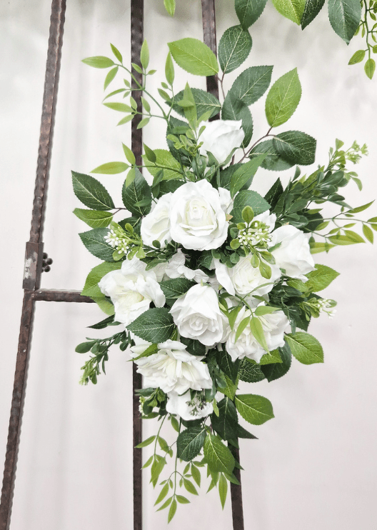 Artificial wedding tieback close-up with white faux roses, layered blooms, small buds and broad green leaves. Made in Melbourne by Flowers For Ever After, shipping Australia and Worldwide.