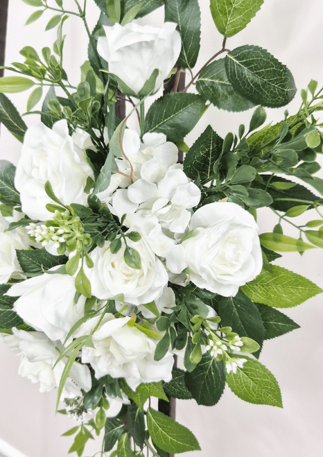 Artificial wedding tieback close-up with white faux roses, clustered white blooms, small buds and broad green leaves. Made in Melbourne by Flowers For Ever After, shipping Australia and Worldwide.