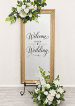 Artificial wedding welcome-sign floral set with white faux roses and green leaves above the frame and in a floor arrangement. Made in Melbourne by Flowers For Ever After, shipping Australia and Worldwide.