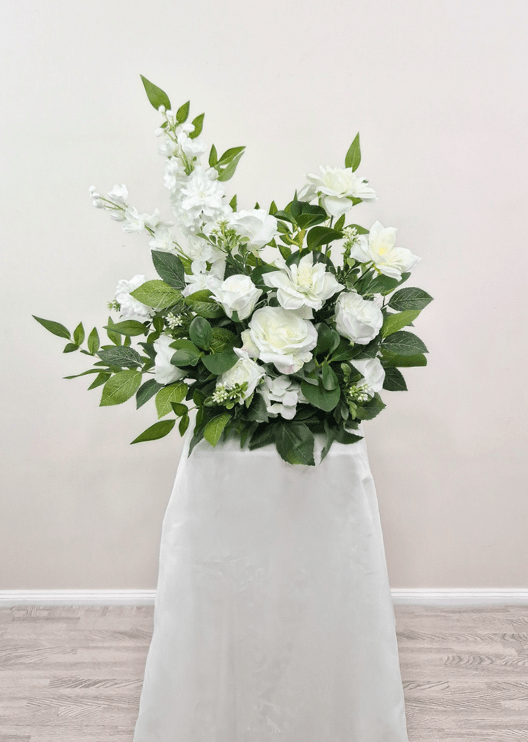 Artificial wedding pedestal arrangement, full view of white faux roses, layered blooms, tall white flower spikes and green leaves. Made in Melbourne by Flowers For Ever After, shipping Australia and Worldwide.