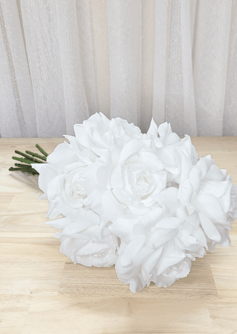 Artificial wedding bridesmaid bouquet laid sideways, showing clustered white faux roses and gathered green stems. Made in Melbourne by Flowers For Ever After, shipping Australia and Worldwide.