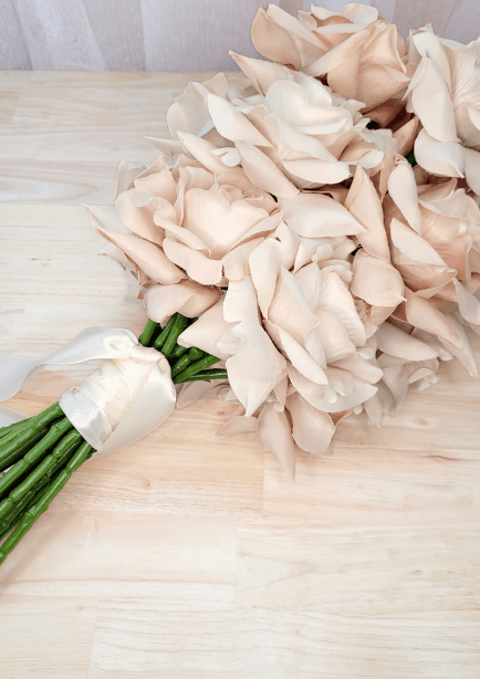 Artificial wedding bouquet laid sideways, showing beige-blush faux roses, ivory ribbon and gathered stems. Made in Melbourne by Flowers For Ever After, shipping Australia and Worldwide.