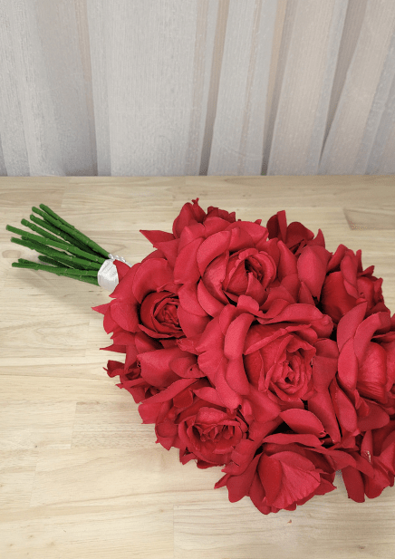 Artificial wedding bouquet laid sideways, showing red faux roses, layered petals and white-wrapped stems. Made in Melbourne by Flowers For Ever After, shipping Australia and Worldwide.