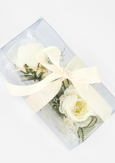 Artificial wedding corsage and boutonniere gift set, overhead view of ivory faux blooms and fine sprigs in a clear ribbon-tied box. For formals, proms and ball occasions. Made in Melbourne by Flowers For Ever After, shipping Australia and Worldwide.