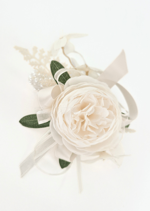 Artificial wedding wrist corsage with a cream faux peony, green leaves, white filler sprigs and ivory ribbon loops. For formals, proms and ball occasions. Made in Melbourne by Flowers For Ever After, shipping Australia and Worldwide.
