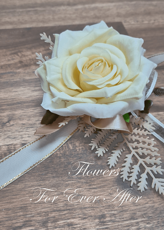 Artificial wedding wrist corsage, angled view of a deep cream faux rose with pale filler flowers, greenery and ivory ribbons. For formals, proms and ball occasions. Made in Melbourne by Flowers For Ever After, shipping Australia and Worldwide.