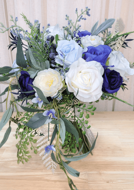 Artificial wedding cascading bouquet with navy, blue and ivory faux roses, white ranunculus, blue sprigs and trailing eucalyptus. Made in Melbourne by Flowers For Ever After, shipping Australia and Worldwide.