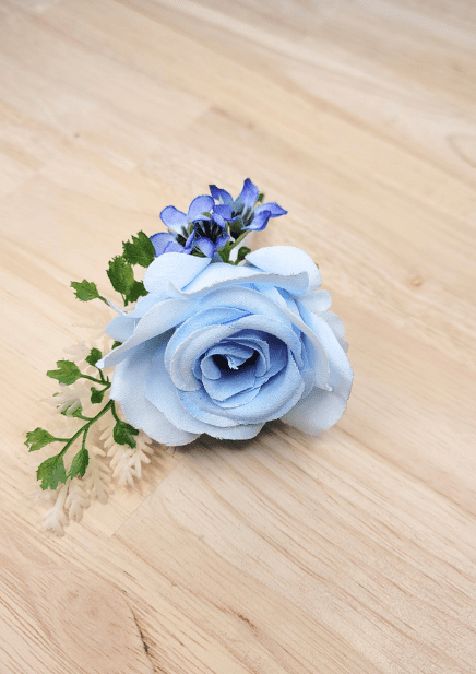 Artificial wedding boutonniere close-up with pale blue faux rose petals, small blue blossoms and cream sprigs. For formals, proms and ball occasions. Made in Melbourne by Flowers For Ever After, shipping Australia and Worldwide.