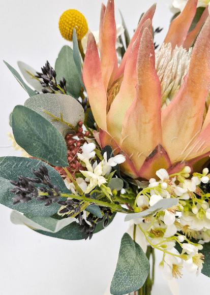Artificial wedding bridesmaid bouquet close-up showing peach faux protea petals, small white flowers and eucalyptus leaves. Made in Melbourne by Flowers For Ever After, shipping Australia and Worldwide.