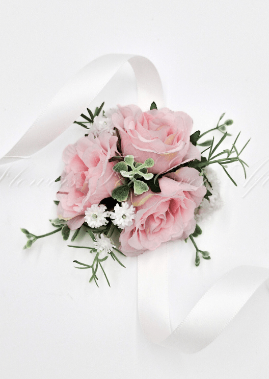 Artificial wedding wrist corsage with pale pink faux roses, small white flowers, green sprigs and trailing ivory ribbons. For formals, proms and ball occasions. Made in Melbourne by Flowers For Ever After, shipping Australia and Worldwide.