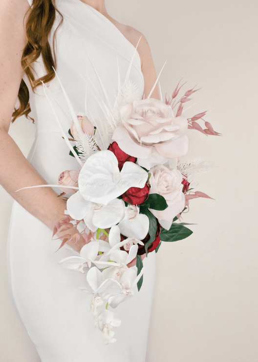 Artificial wedding cascading bridal bouquet with blush faux roses, red blooms, white orchids, pink foliage and white feathery sprigs. Made in Melbourne by Flowers For Ever After, shipping Australia and Worldwide.