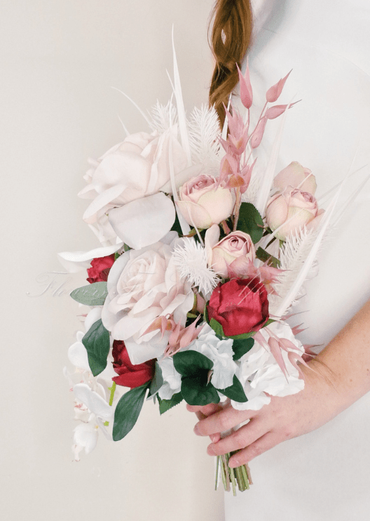Artificial wedding cascading bridal bouquet, angled view of blush faux roses, red flowers, white orchids and pink foliage. Made in Melbourne by Flowers For Ever After, shipping Australia and Worldwide.