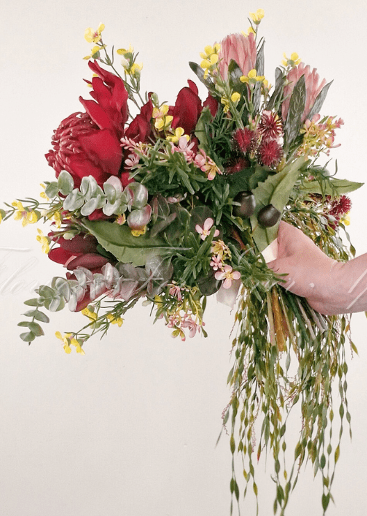Artificial wedding bridal bouquet, reverse view of red faux waratah, pink protea, yellow flowers, seed pods and trailing greenery. Made in Melbourne by Flowers For Ever After, shipping Australia and Worldwide.