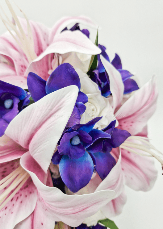 Artificial wedding bridesmaid posy, front view of pink faux lilies, purple orchids and green foliage. Made in Melbourne by Flowers For Ever After, shipping Australia and Worldwide.