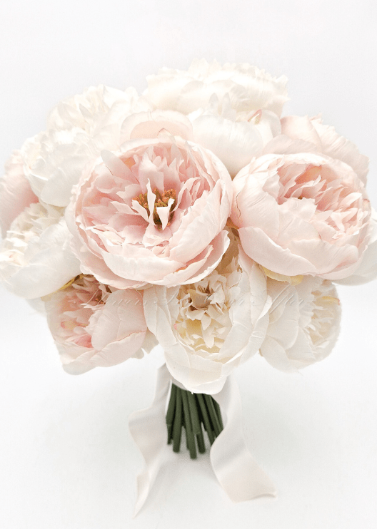 Artificial wedding bridesmaid posy, angled view of white and pale blush faux peonies and green leaves. Made in Melbourne by Flowers For Ever After, shipping Australia and Worldwide.