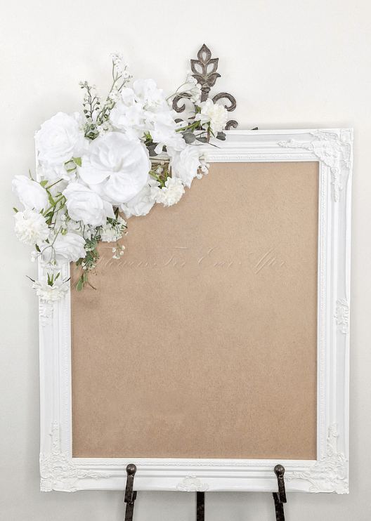 Artificial wedding sign decoration with white faux roses, white blooms and branching white sprigs at the upper corner. Made in Melbourne by Flowers For Ever After, shipping Australia and Worldwide.