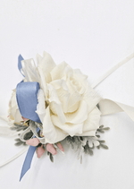 Artificial wedding wrist corsage, angled view of cream faux roses, dusty blue ribbon, pink berries and grey-green foliage. For formals, proms and ball occasions. Made in Melbourne by Flowers For Ever After, shipping Australia and Worldwide.