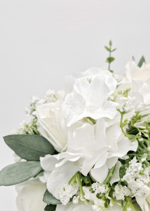 Artificial wedding bouquet close-up with white faux roses, white blooms and fine white sprigs among eucalyptus leaves. Made in Melbourne by Flowers For Ever After, shipping Australia and Worldwide.