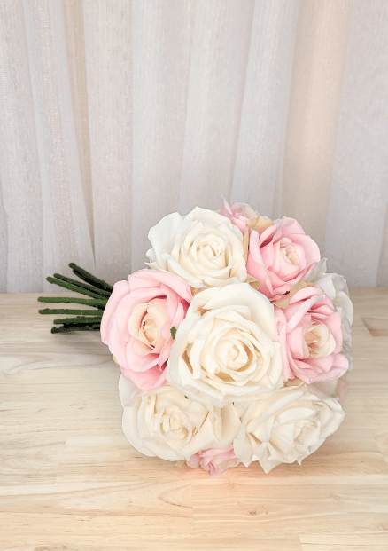 Artificial wedding bouquet laid sideways, showing pink and ivory faux roses and gathered green stems. Made in Melbourne by Flowers For Ever After, shipping Australia and Worldwide.