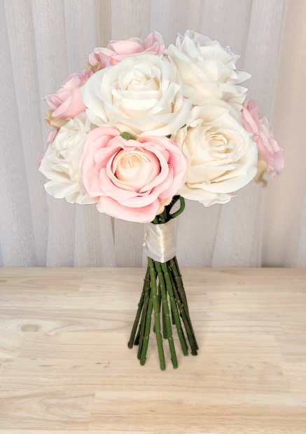 Artificial wedding bouquet with pink and ivory faux roses, ivory ribbon wrapping and gathered green stems. Made in Melbourne by Flowers For Ever After, shipping Australia and Worldwide.