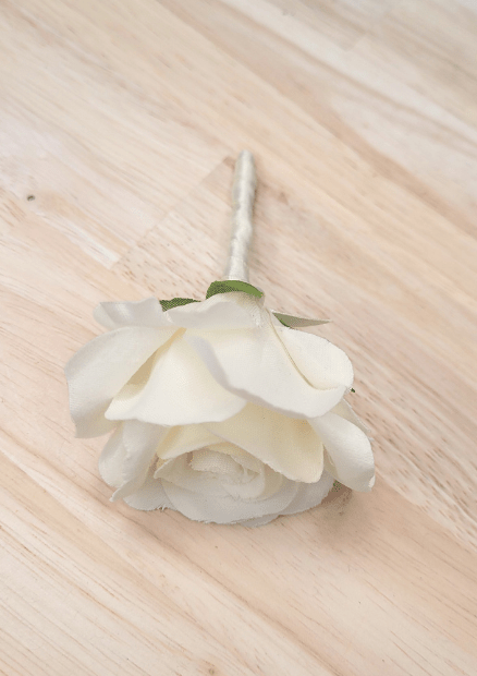 Artificial wedding boutonniere close-up showing ivory faux rose petals, green sepals and ivory-wrapped stem. For formals, proms and ball occasions. Made in Melbourne by Flowers For Ever After, shipping Australia and Worldwide.