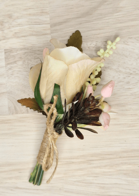 Artificial wedding boutonniere with cream faux rosebud, pale pink buds, dark sprigs, green leaves and twine-wrapped stem. For formals, proms and ball occasions. Made in Melbourne by Flowers For Ever After, shipping Australia and Worldwide.