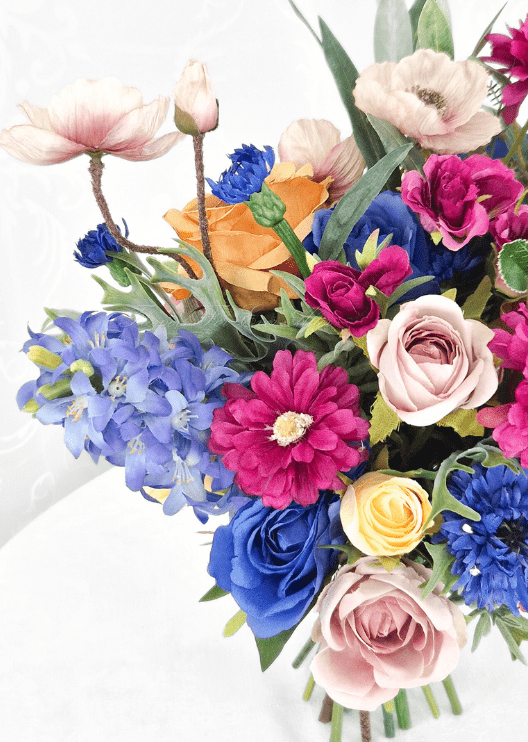 Artificial wedding bouquet close-up with blue and blush faux roses, magenta dahlia, pale pink poppies and blue flower spikes. Made in Melbourne by Flowers For Ever After, shipping Australia and Worldwide.
