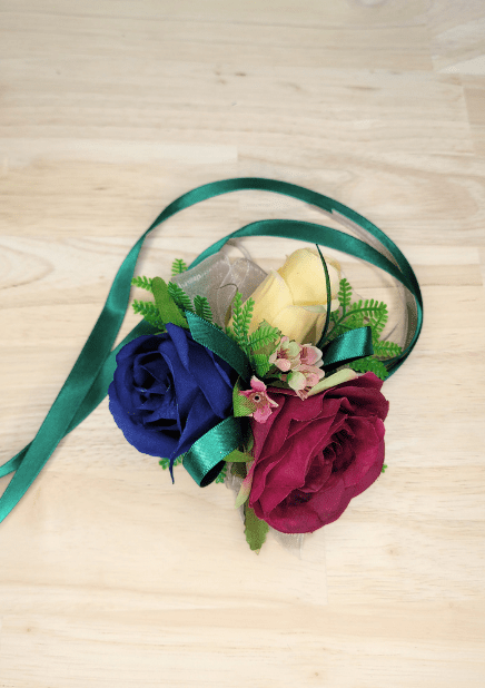 Artificial wedding wrist corsage with navy, magenta and cream faux roses, small pink flowers, fern-like leaves and green ribbon tails. For formals, proms and ball occasions. Made in Melbourne by Flowers For Ever After, shipping Australia and Worldwide.