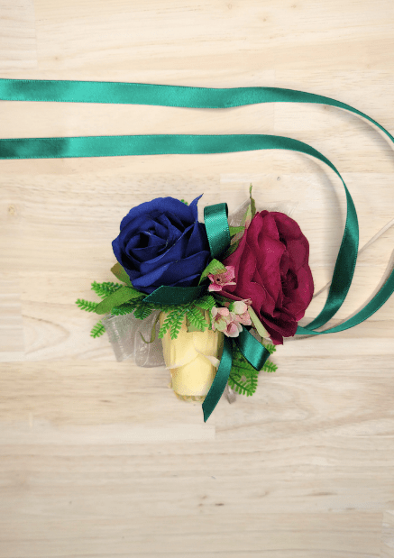 Artificial wedding wrist corsage, overhead view of navy, magenta and cream faux roses, pink blossoms and green ribbons. For formals, proms and ball occasions. Made in Melbourne by Flowers For Ever After, shipping Australia and Worldwide.