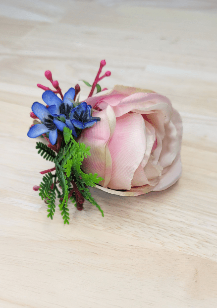 Artificial wedding boutonniere close-up with blush faux rosebud, blue flowers, magenta sprigs and fern-like greenery. For formals, proms and ball occasions. Made in Melbourne by Flowers For Ever After, shipping Australia and Worldwide.