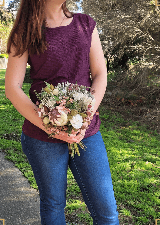 Artificial wedding bridal bouquet held by a bride, with native-style faux flowers and green foliage. Made in Melbourne by Flowers For Ever After, shipping Australia and Worldwide.